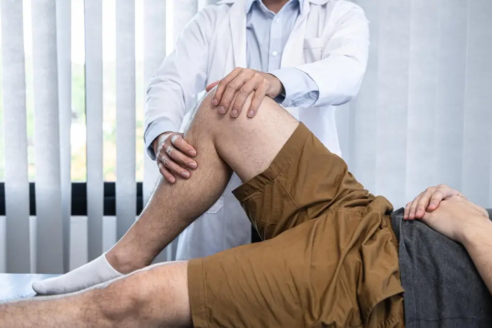 Dr Sanjeev Jain examining a patient during revision knee replacement surgery consultation